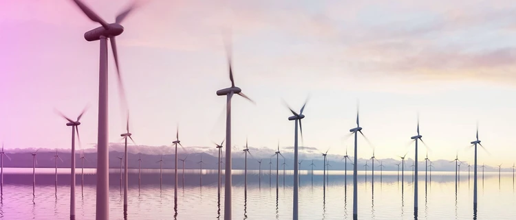 Pale eoliche industriali in movimento in un paesaggio naturalistico acquatico.