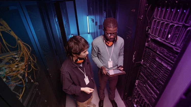 Two IT specialists monitoring cloud & infrastructure performance within a high-security data center.